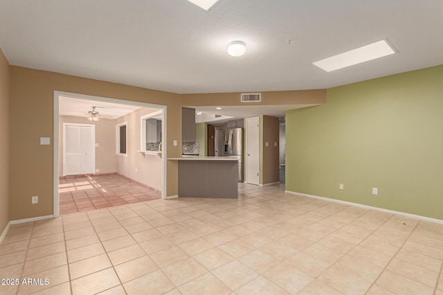 unfurnished living room featuring light tile patterned floors and ceiling fan