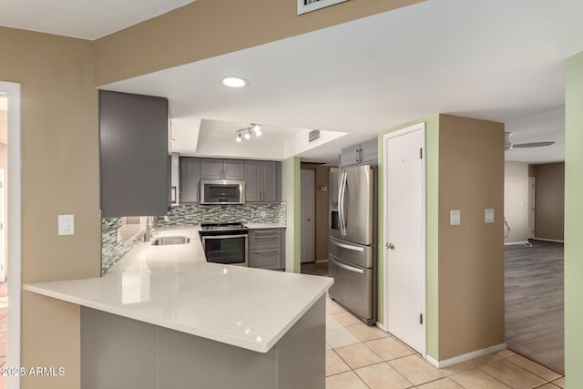 kitchen featuring kitchen peninsula, stainless steel appliances, ceiling fan, sink, and light tile patterned flooring