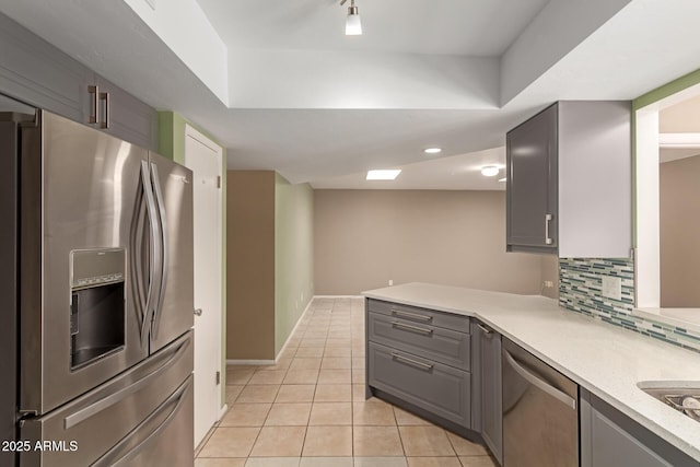 kitchen featuring decorative backsplash, gray cabinets, light tile patterned floors, and stainless steel appliances