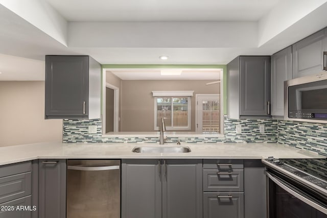 kitchen with backsplash, gray cabinets, sink, and stainless steel appliances