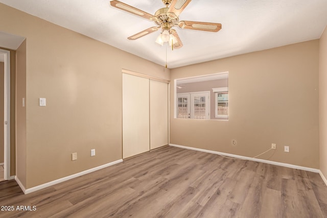 unfurnished bedroom featuring hardwood / wood-style floors, a closet, and ceiling fan