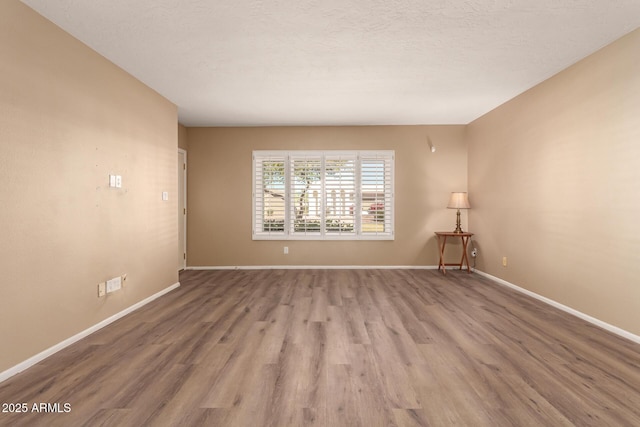 unfurnished room featuring light hardwood / wood-style floors and a textured ceiling