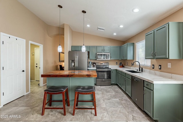 kitchen featuring a breakfast bar, sink, vaulted ceiling, hanging light fixtures, and appliances with stainless steel finishes