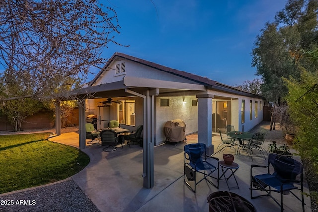 back house at dusk with a patio and ceiling fan