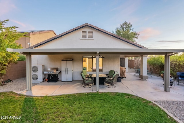 back house at dusk featuring a yard, ceiling fan, and a patio area