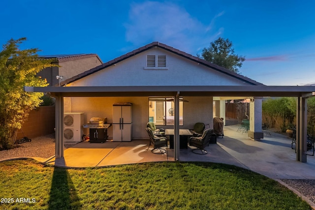 back house at dusk with a patio, a yard, and ceiling fan