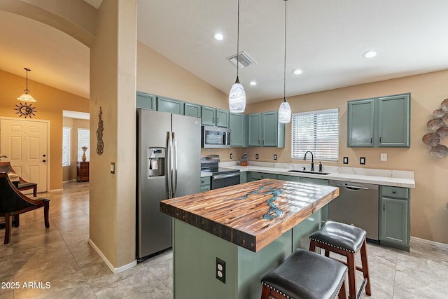 kitchen with a kitchen bar, sink, a center island, hanging light fixtures, and appliances with stainless steel finishes