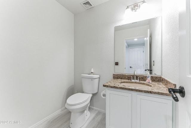 bathroom with wood-type flooring, vanity, and toilet