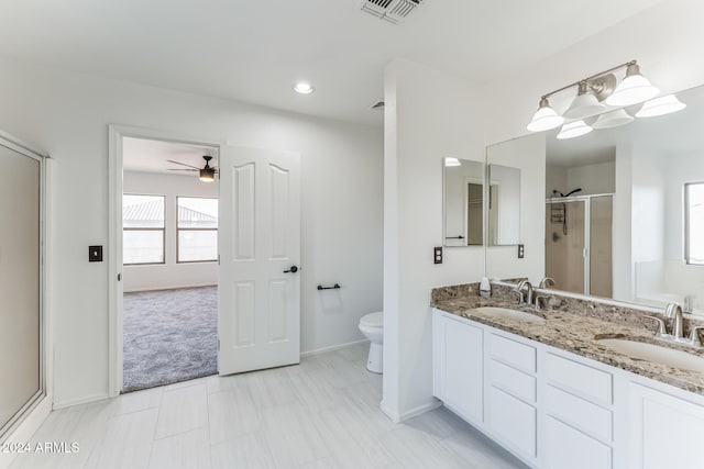 bathroom featuring ceiling fan, toilet, a shower with door, and vanity