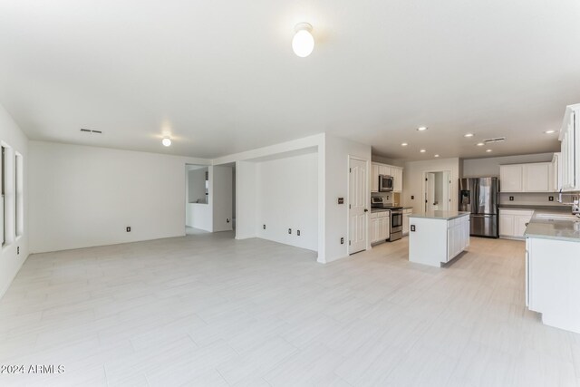 kitchen featuring appliances with stainless steel finishes, a center island, white cabinetry, and sink