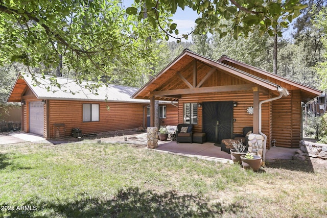 rear view of house featuring a garage, metal roof, an outbuilding, a yard, and a patio area