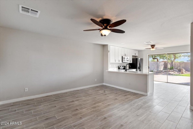 kitchen with light hardwood / wood-style flooring, white cabinetry, kitchen peninsula, and appliances with stainless steel finishes