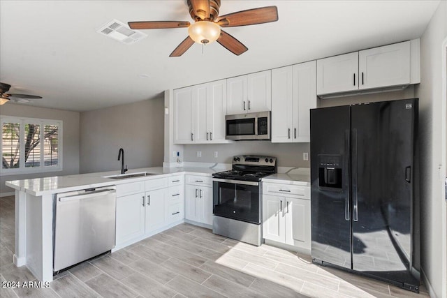 kitchen featuring white cabinets, kitchen peninsula, appliances with stainless steel finishes, and sink