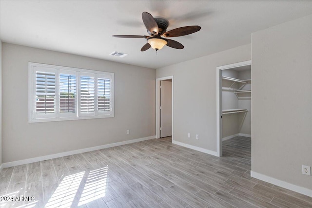 unfurnished bedroom with ceiling fan, light hardwood / wood-style flooring, a closet, and a walk in closet