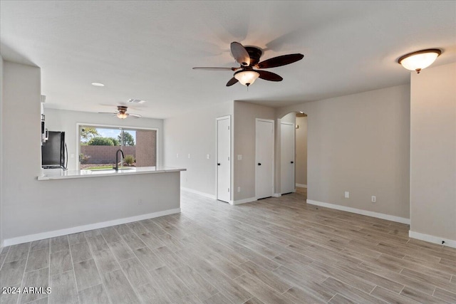 unfurnished living room with light hardwood / wood-style flooring and ceiling fan