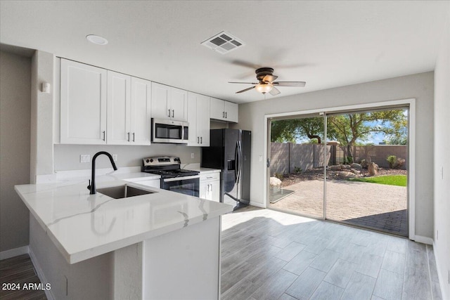 kitchen featuring white cabinetry, kitchen peninsula, stainless steel appliances, light wood-type flooring, and sink