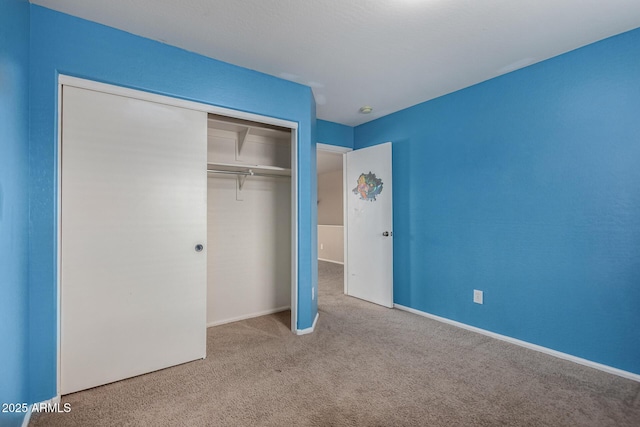 unfurnished bedroom featuring light carpet and a closet