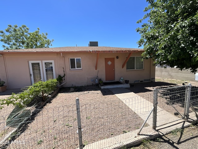 view of front facade featuring a shingled roof, fence, and stucco siding