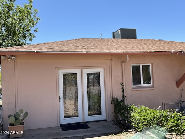 view of exterior entry featuring roof with shingles and stucco siding