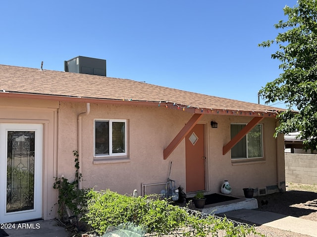 view of front facade featuring entry steps, roof with shingles, fence, and stucco siding