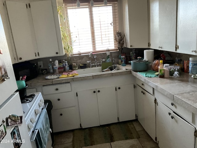 kitchen featuring light countertops, backsplash, a sink, and white cabinetry