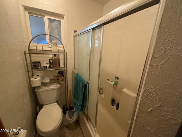 bathroom with a stall shower, a textured wall, and toilet