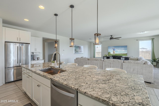 kitchen featuring ceiling fan, stainless steel appliances, white cabinetry, and sink