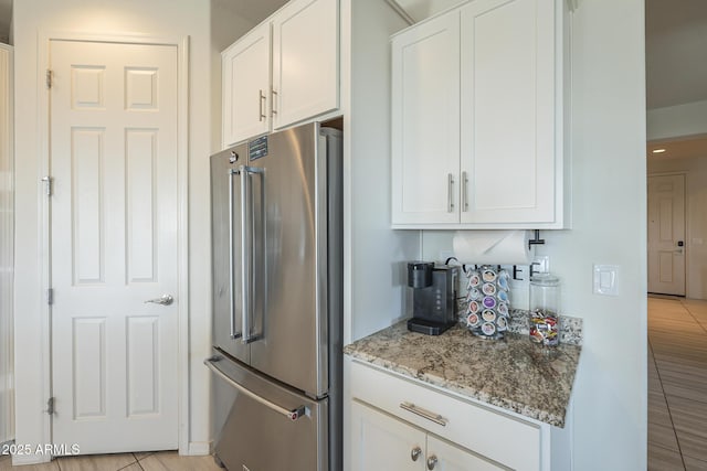 kitchen with light tile patterned floors, white cabinetry, light stone counters, and high end fridge