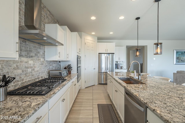 kitchen featuring stainless steel appliances, wall chimney exhaust hood, white cabinetry, and sink