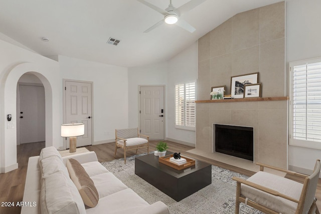 living room featuring a large fireplace, ceiling fan, light hardwood / wood-style floors, and vaulted ceiling