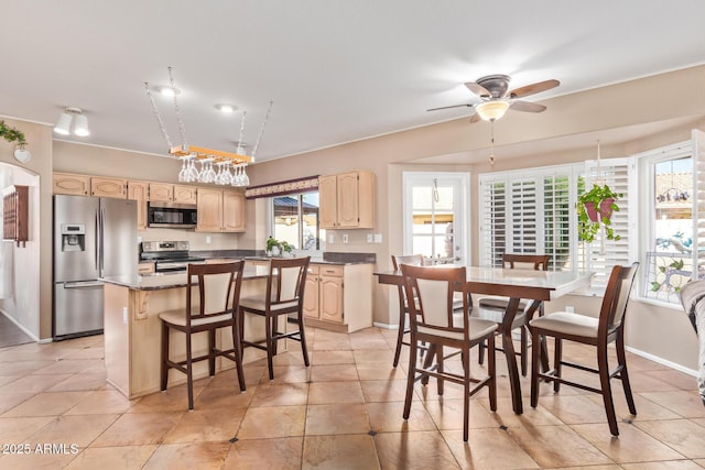 kitchen with light tile patterned floors, a breakfast bar, ceiling fan, stainless steel appliances, and a kitchen island