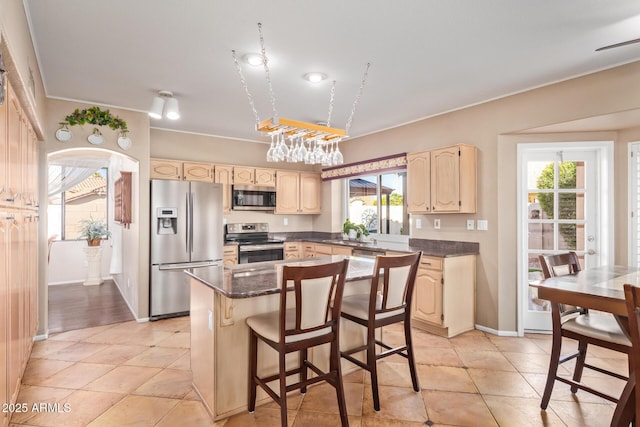 kitchen with a kitchen island, appliances with stainless steel finishes, a kitchen bar, light tile patterned floors, and crown molding