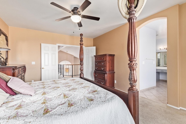 bedroom with ceiling fan, light colored carpet, and ensuite bathroom