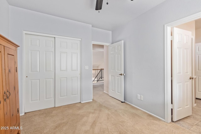 unfurnished bedroom featuring light colored carpet, a closet, and ceiling fan