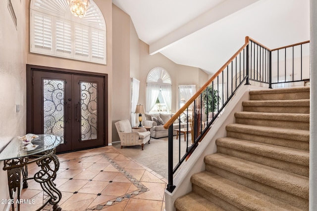 tiled entryway featuring high vaulted ceiling, an inviting chandelier, beam ceiling, and french doors