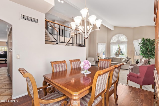 dining area with an inviting chandelier, hardwood / wood-style flooring, and lofted ceiling with beams