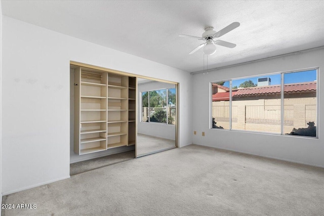 unfurnished room featuring ceiling fan, carpet, and a textured ceiling