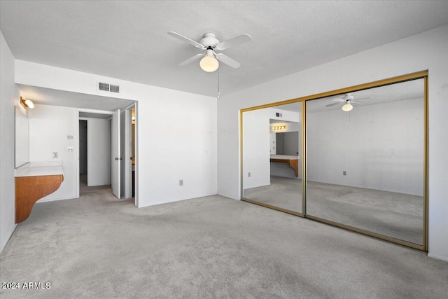 unfurnished bedroom featuring a closet, ceiling fan, light carpet, and a textured ceiling