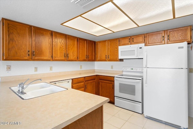 kitchen with a textured ceiling, sink, light tile patterned floors, and white appliances