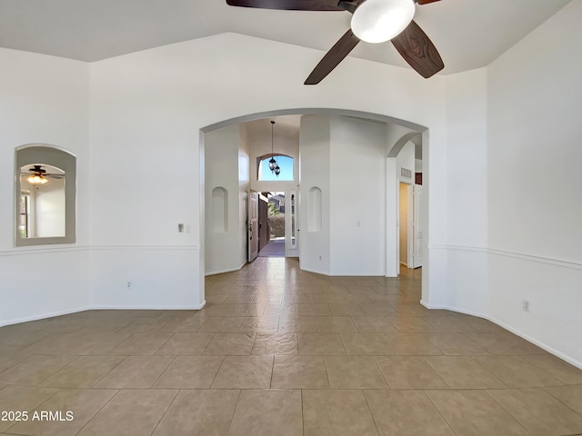 unfurnished room with ceiling fan, high vaulted ceiling, and light tile patterned floors