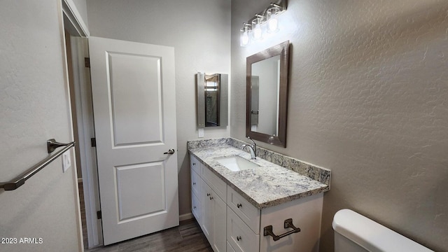 bathroom with vanity, wood-type flooring, and toilet