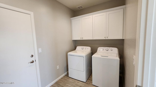 laundry area featuring independent washer and dryer, cabinets, and light hardwood / wood-style floors