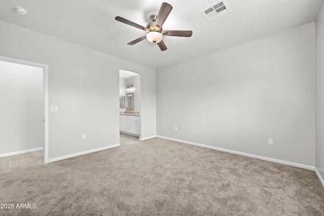 unfurnished bedroom with ensuite bathroom, light carpet, and ceiling fan