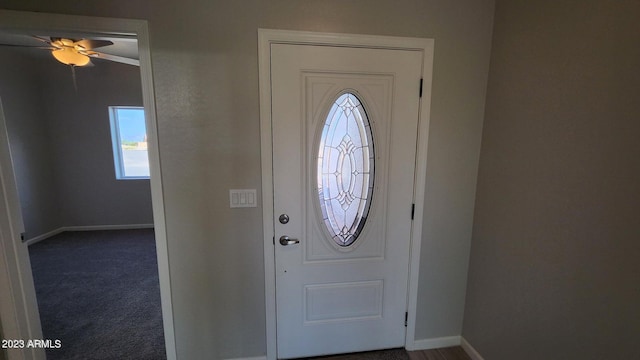 entrance foyer featuring ceiling fan and dark colored carpet