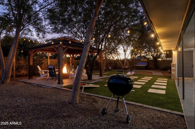 yard at dusk featuring a gazebo, an outdoor fire pit, and a patio