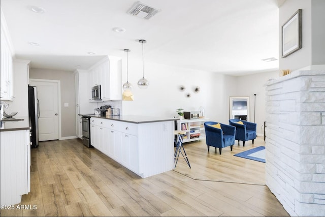 kitchen featuring light hardwood / wood-style floors, stainless steel appliances, white cabinetry, and pendant lighting