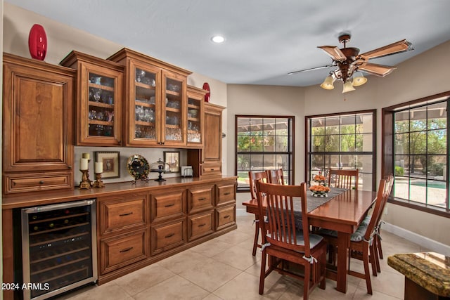 tiled dining area with ceiling fan, beverage cooler, and a healthy amount of sunlight