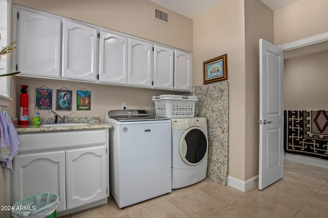 clothes washing area featuring light tile patterned flooring, cabinets, washer and dryer, and sink