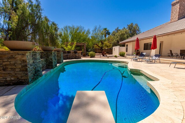 view of pool featuring a patio, pool water feature, and a diving board