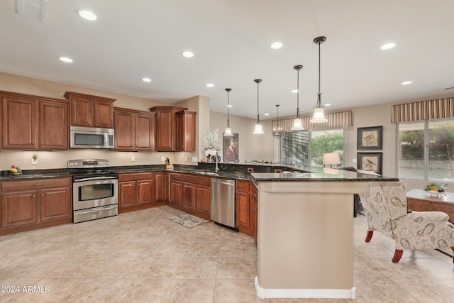 kitchen featuring sink, dark stone counters, kitchen peninsula, pendant lighting, and stainless steel appliances